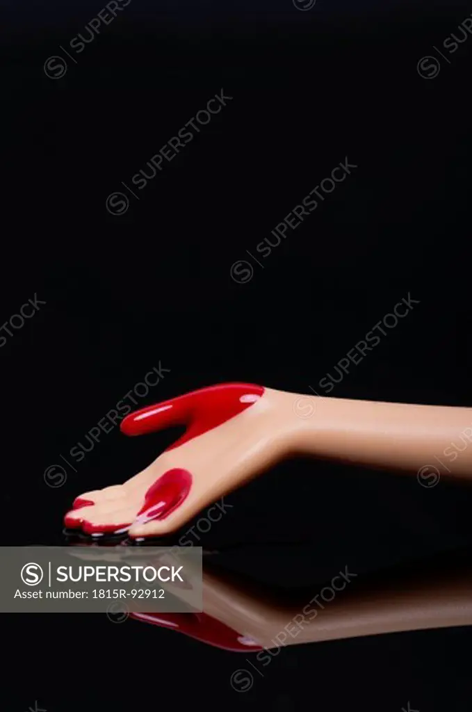 Close up of doll hand with blood on black background