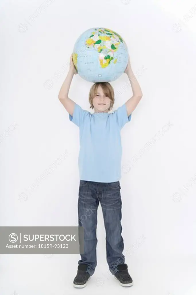 Germany, Bavaria, Ebenhausen, Boy holding earth globe against white background, smiling, portrait