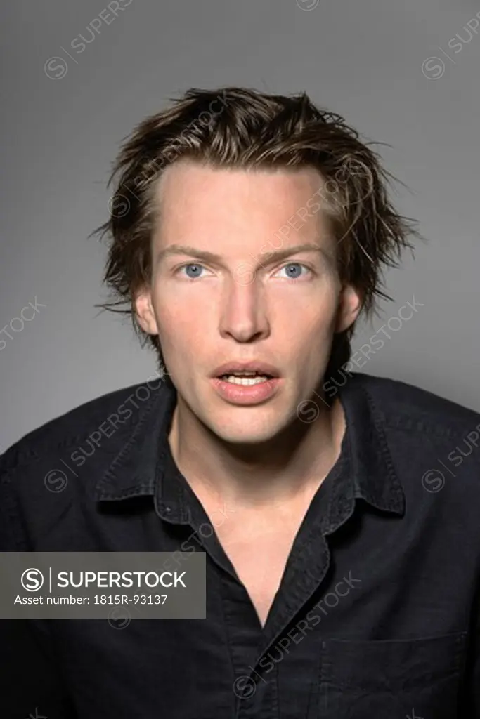 Man looking shocked against grey background, close up, portrait