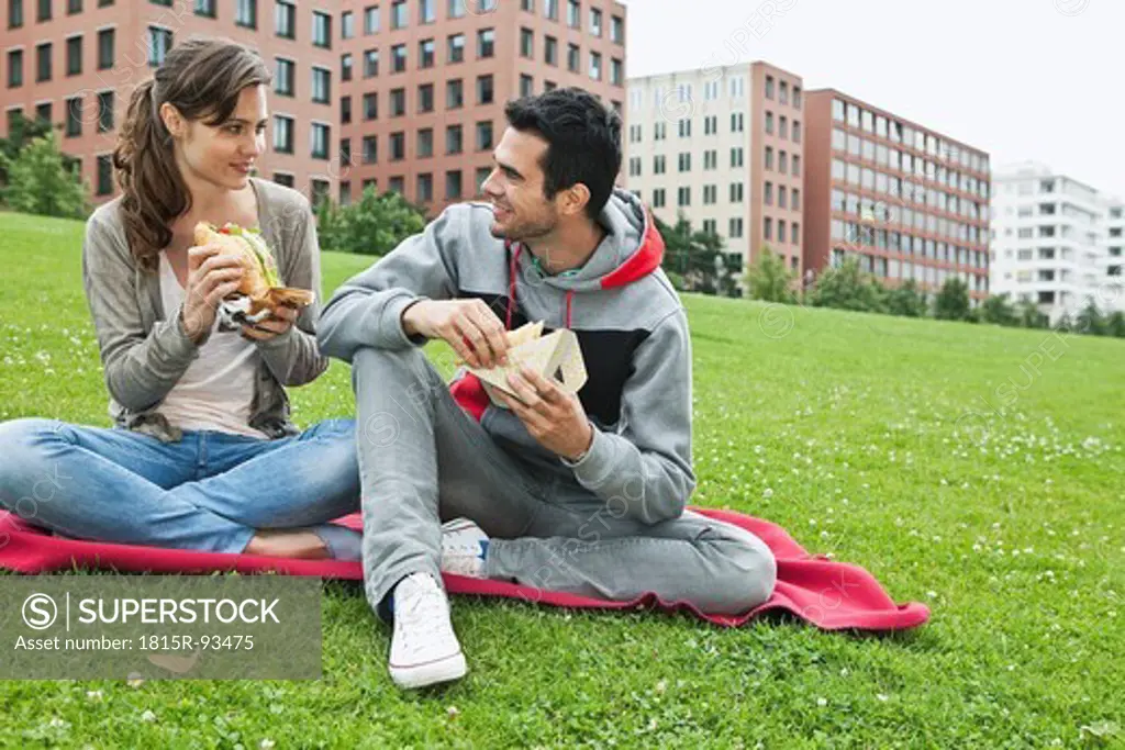 Germany, Berlin, Couple eating food in park