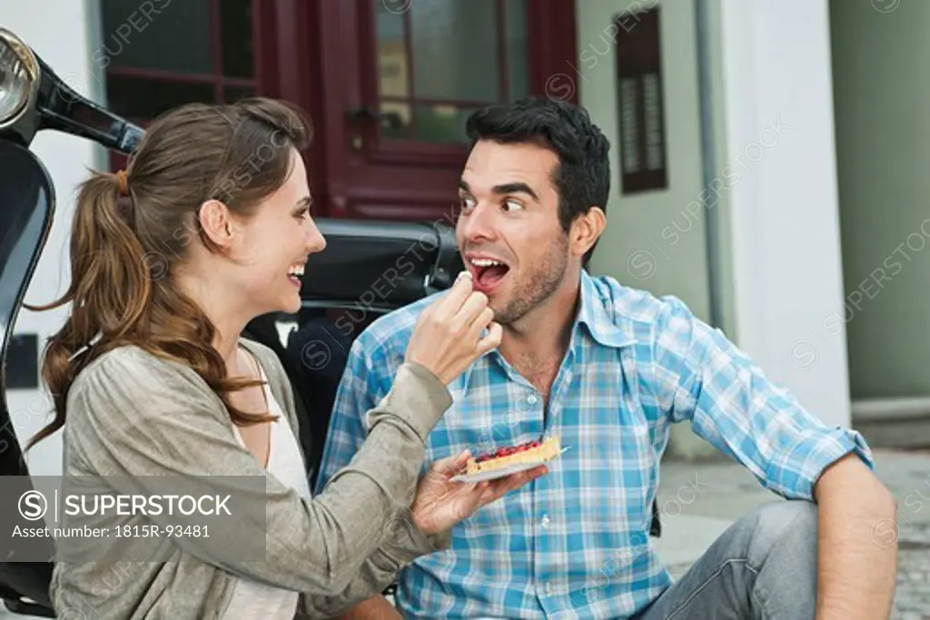 Germany, Berlin, Couple eating snacks on sidewalk