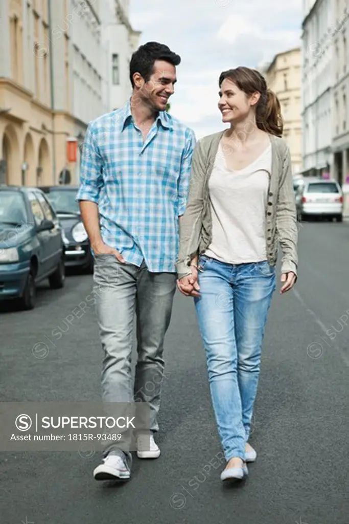 Germany, Berlin, Couple walking hand in hand through city street
