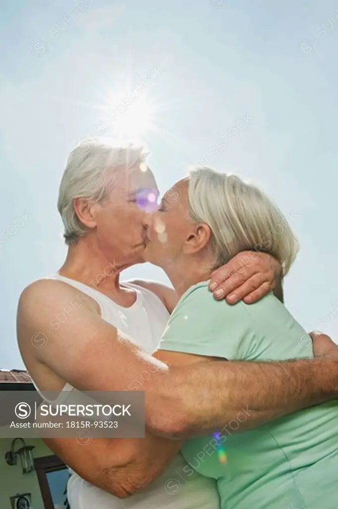 Germany, Bavaria, Man and woman kissing each other against sky, smiling