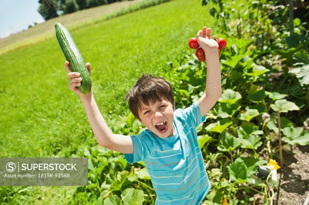 Germany, Bavaria, Boy holding vegetables in garden, smiling, portrait