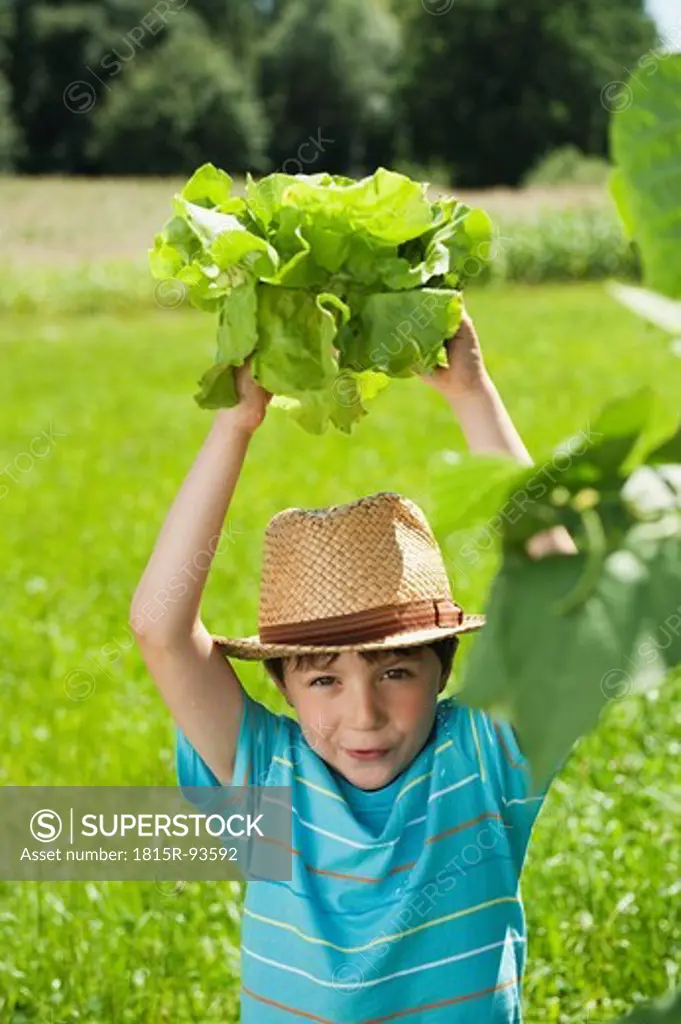 Germany, Bavaria, Boy in garden holding vegetables, smiling, portrait