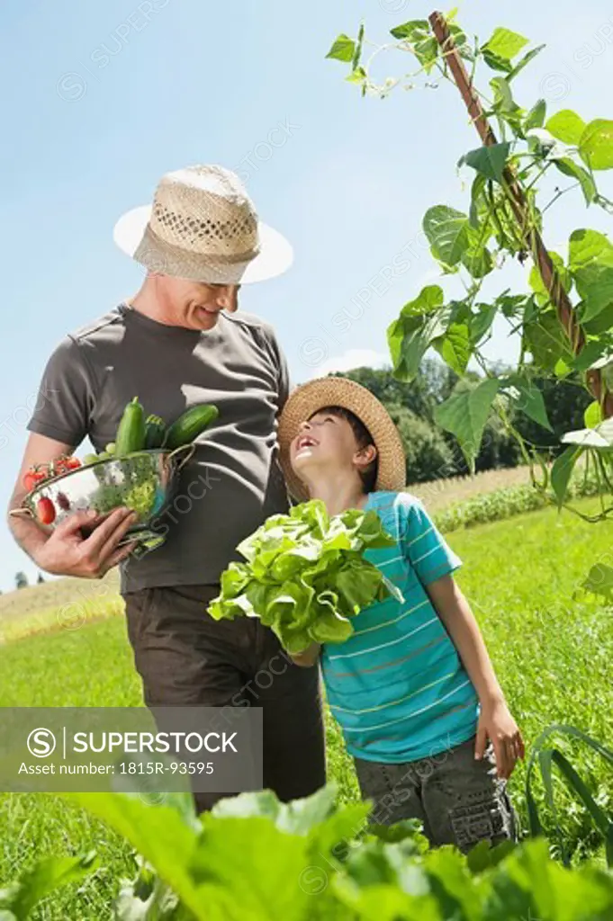 Germany, Bavaria, Grandfather with grandson in vegetable garden, smiling