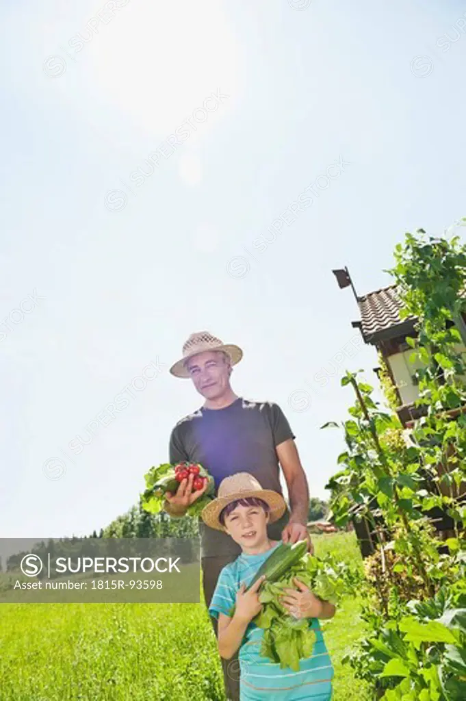 Germany, Bavaria, Grandfather with grandson in vegetable garden, smiling, portrait