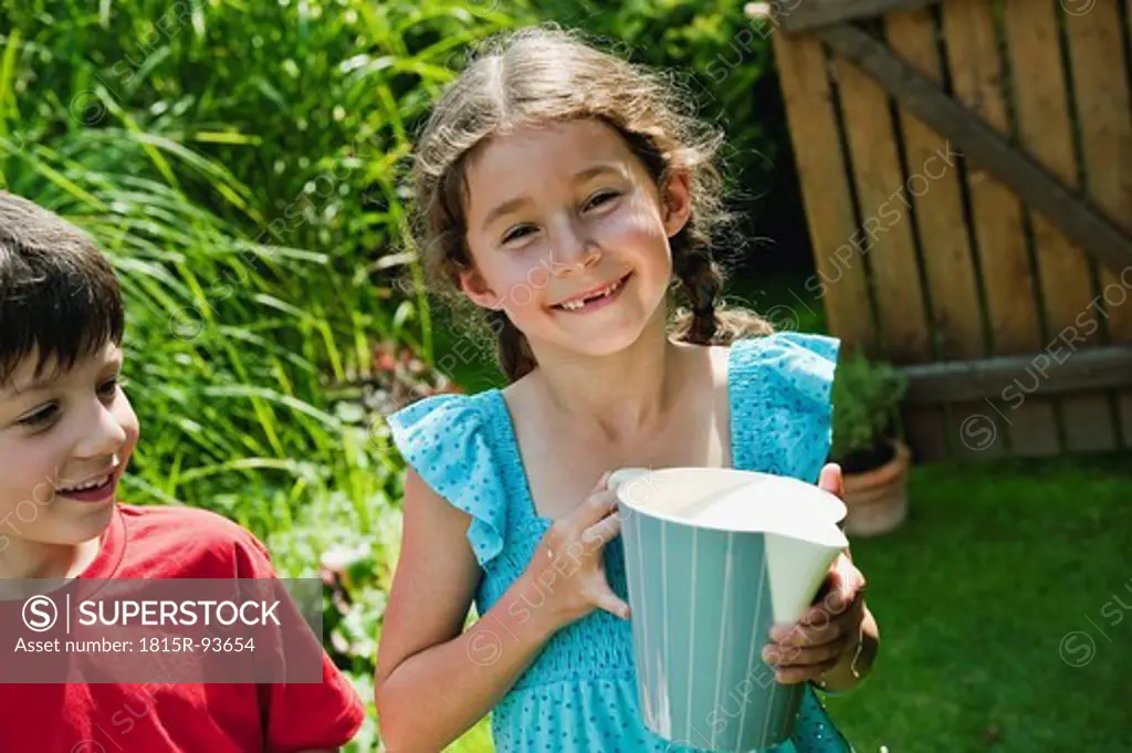 Germany, Bavaria, Girl holding pitcher with boy smiling