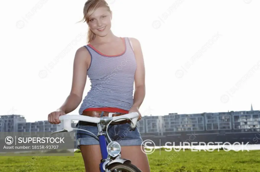 Germany, Cologne, Young woman with bicycle, smiling, portrait