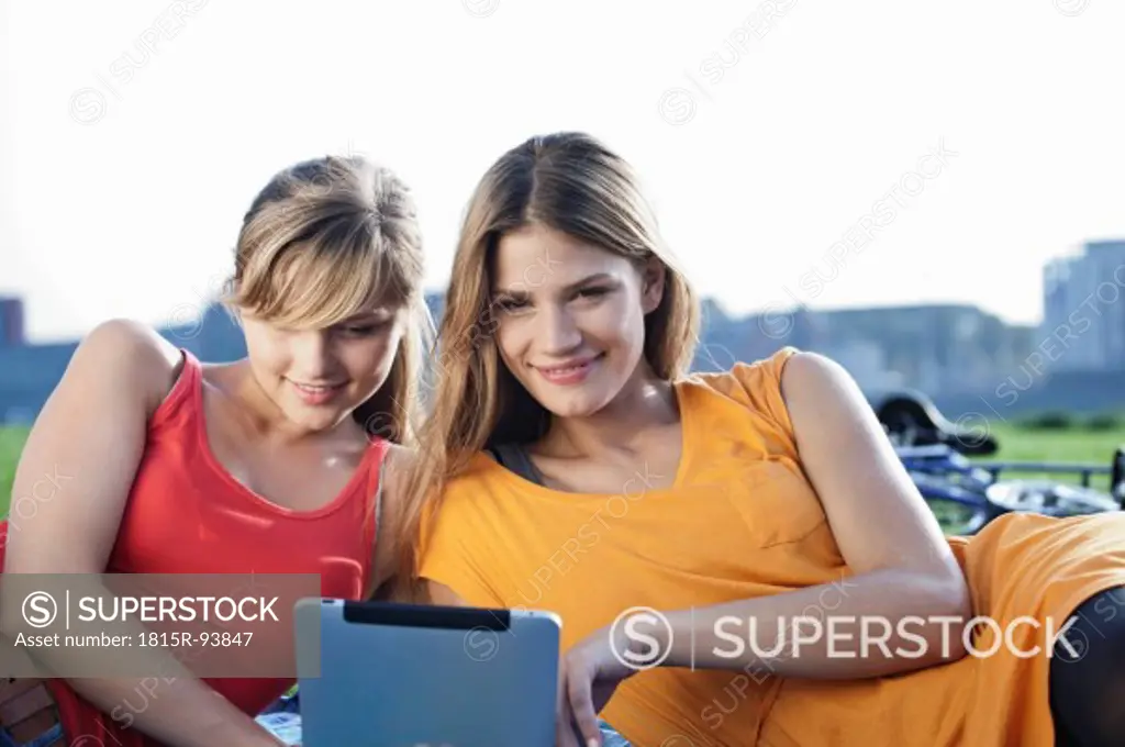 Germany, Cologne, Young woman using digital tablet, smiling