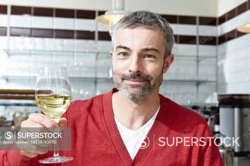 Germany, Cologne, Mature man drinking wine, smiling, portrait