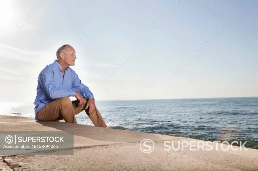 Spain, Mallorca, Senior man sitting at sea shore