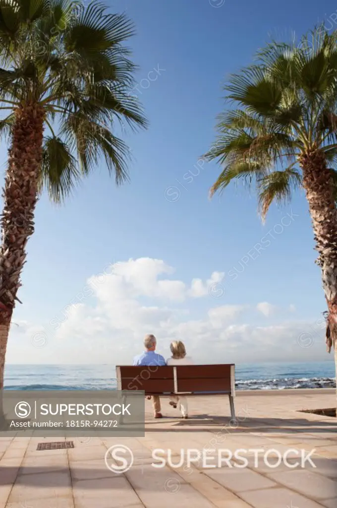 Spain, Mallorca, Senior couple sitting on bench at sea shore