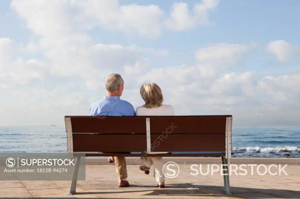 Spain, Mallorca, Senior couple sitting on bench at sea shore