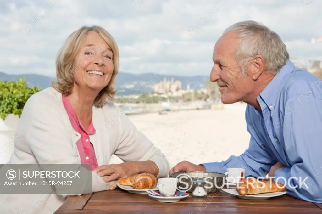 Spain, Mallorca, Senior couple in restaurant at beach, smiling