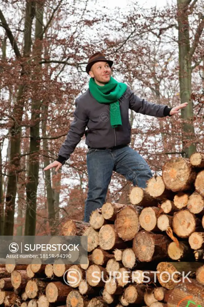 Germany, Berlin, Wandlitz, Young man standing on stack of wood