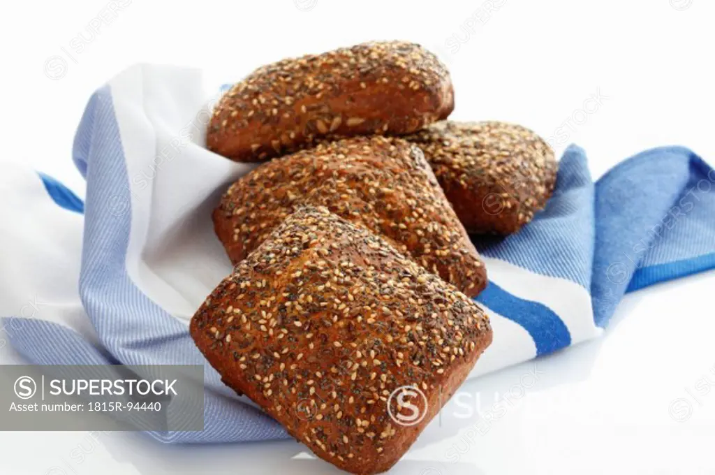 Granary roll with seed on kitchen towel, close up