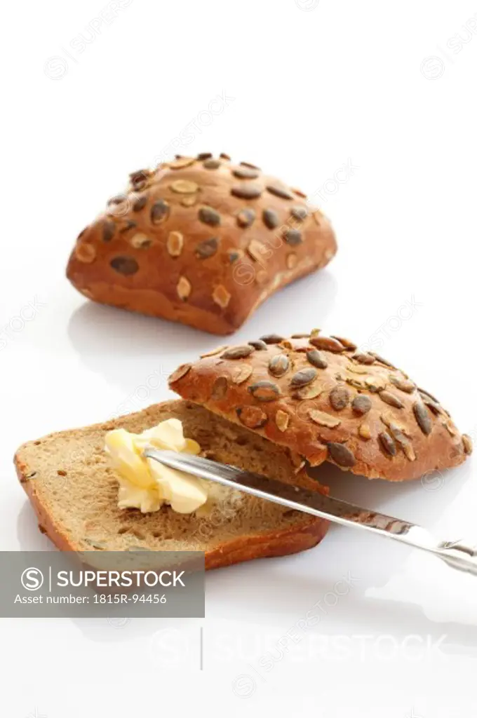 Wholemeal bread with butter and knife on white background