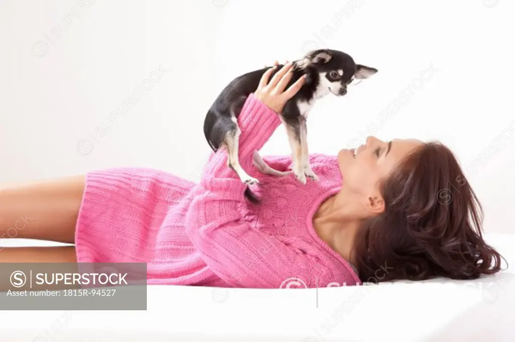 Young woman with chihuahua on bed
