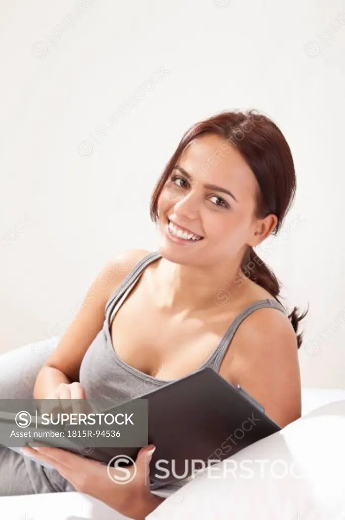 Young woman using tablet pc, smiling, portrait