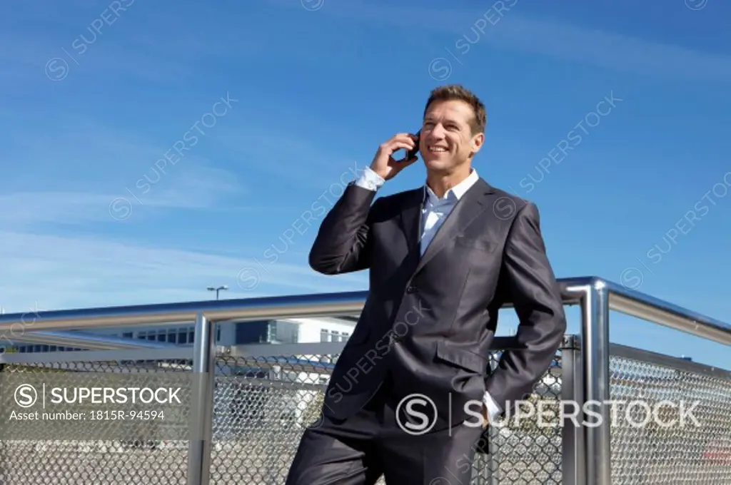 Germany, Bavaria, Munich,Businessman talking on cell phone, smiling
