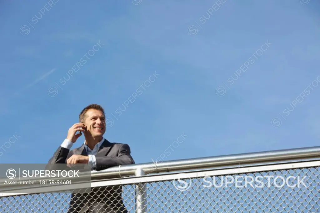 Germany, Bavaria, Munich, Businessman talking on cell phone, smiling