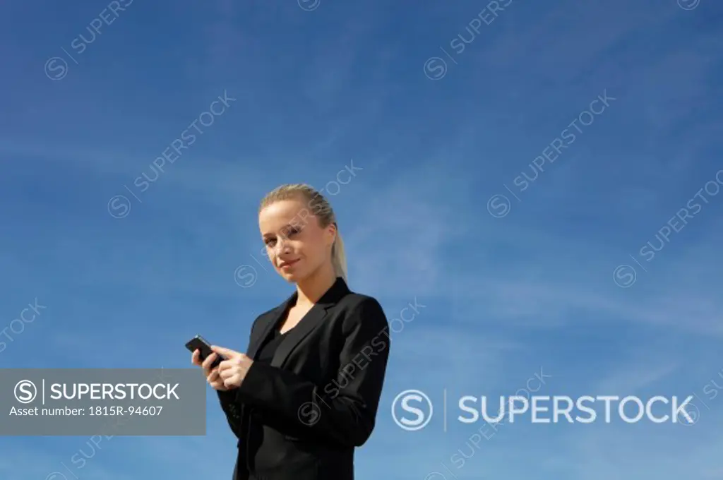 Germany, Bavaria, Munich, Businesswoman with cell phone, smiling, portrait