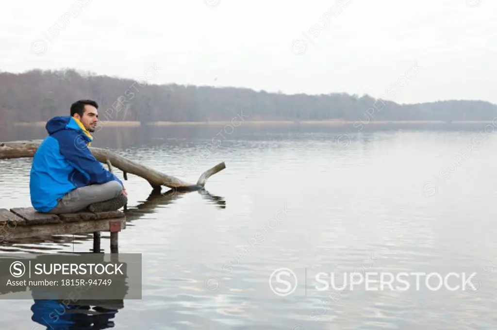 Germany, Berlin, Wandlitz, Young man sitting on pier