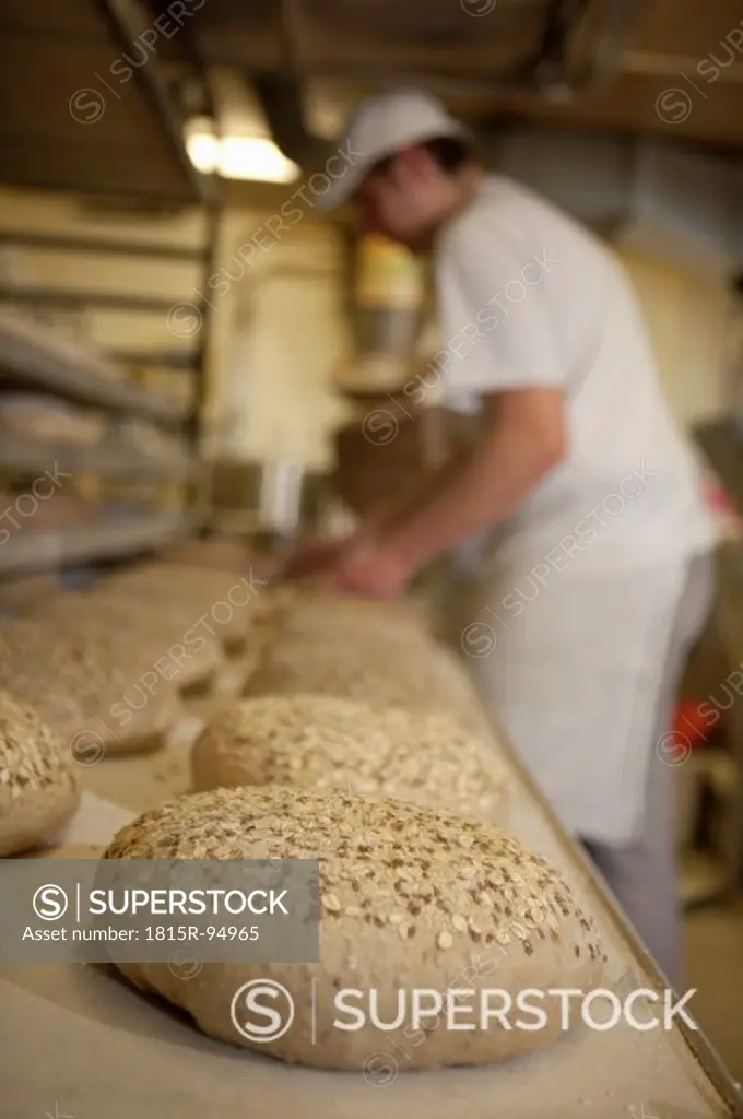 Germany, Bavaria, Munich, Baker putting bread loaf in baking tray