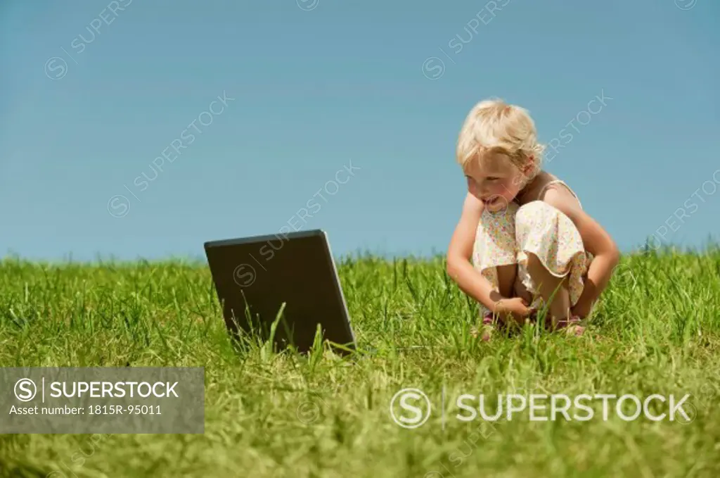 Germany, Bavaria, Girl with laptop sitting in grass