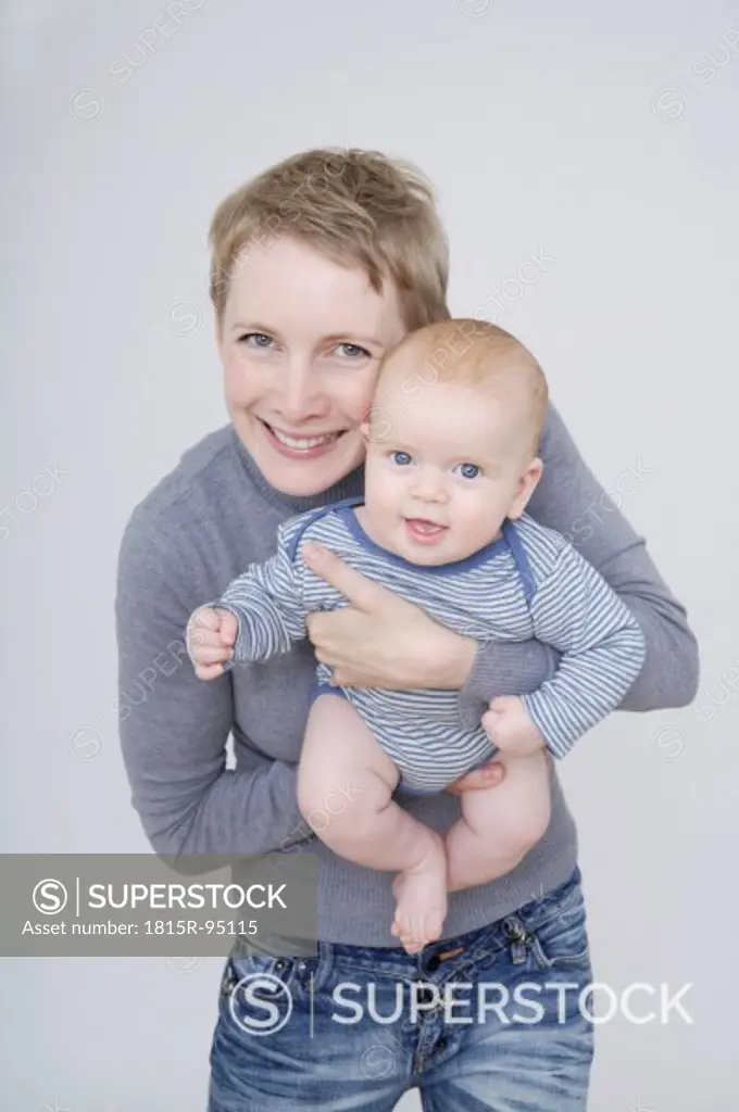 Mother holding baby boy, smiling, portrait
