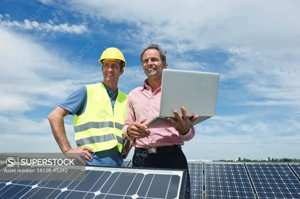 Germany, Munich, Engineers with laptop in solar plant