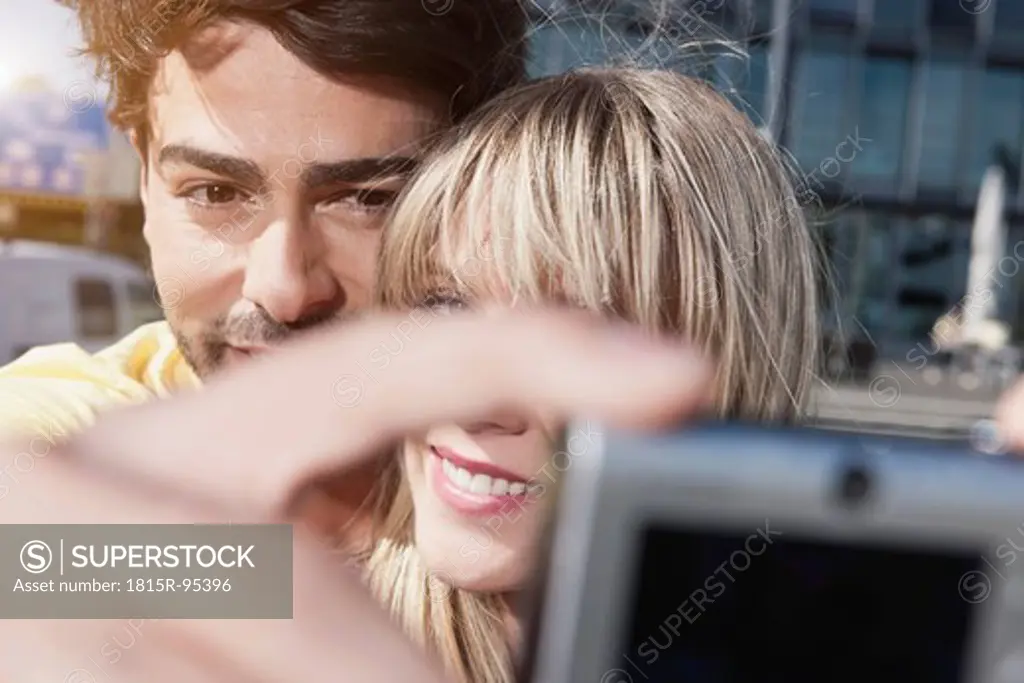 Germany, Cologne, Young couple using cell phone for capturing photo, smiling, close up