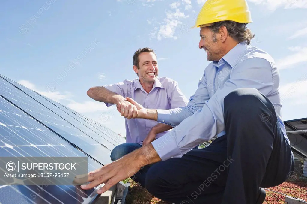 Germany, Munich, Man shaking hands with engineer in solar plant, smiling