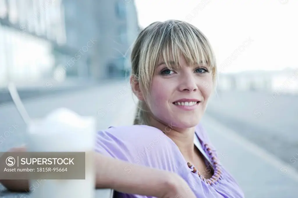 Germany, Cologne, Young woman smiling with coffee in foreground