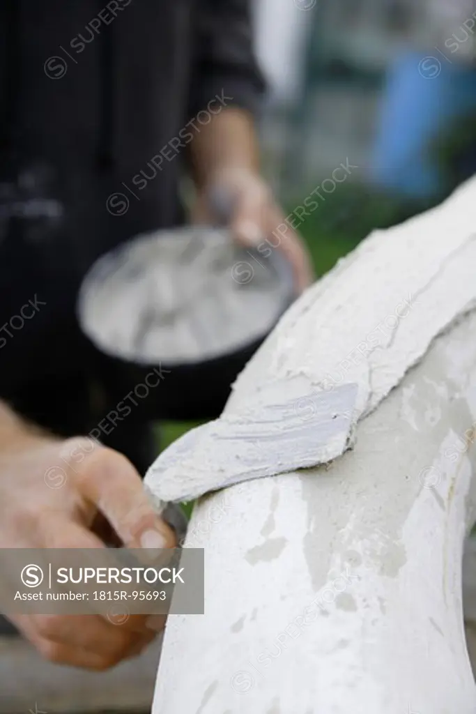 Germany, Upper Bavaria, Munich, Schaeftlarn, Sculptor applying plaster with trowel