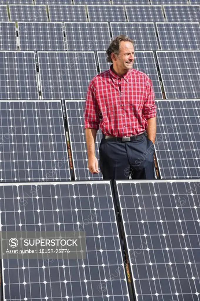 Germany, Munich, Mature man standing in solar plant, smiling