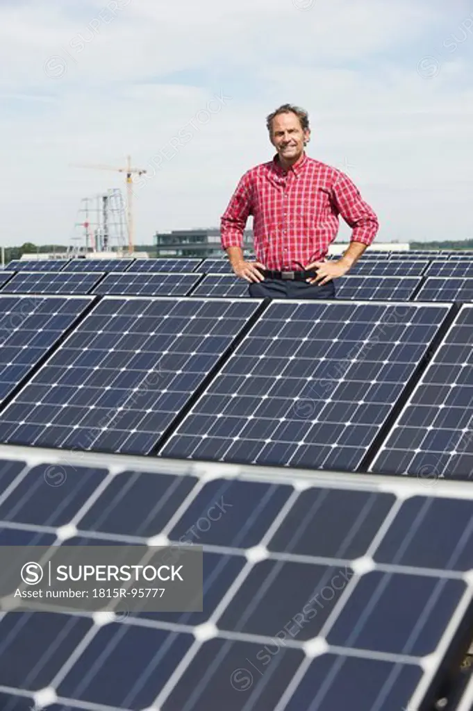Germany, Munich, Mature man standing in solar plant, smiling, portrait