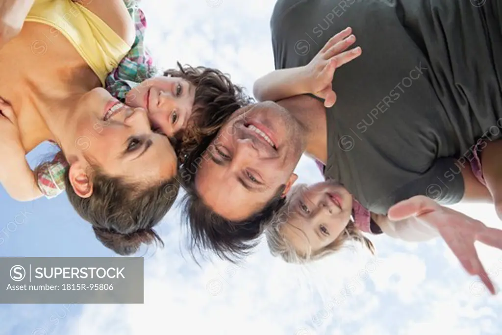 Germany, Bavaria, Parents giving children piggyback ride in park, smiling
