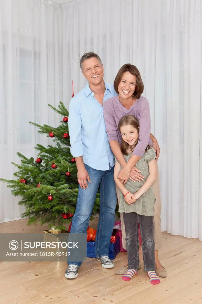 Germany, Munich, Family standing by christmas tree, smiling, portrait