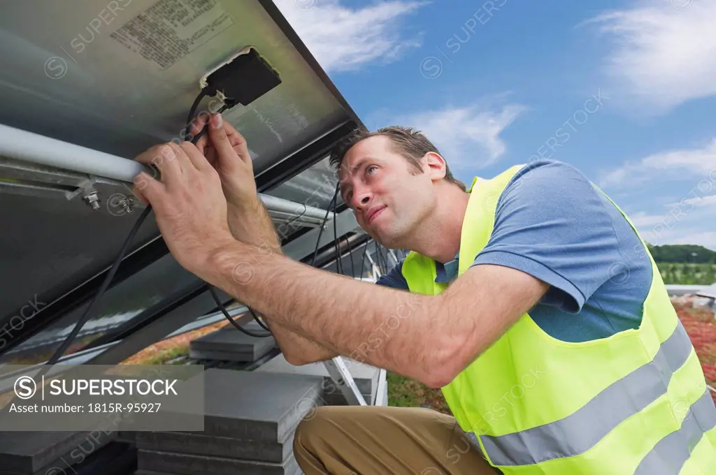 Germany, Munich, Technician fixing cable of solar panel