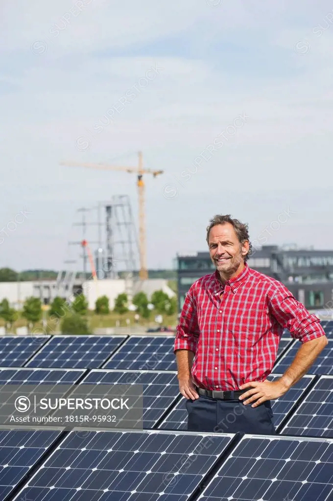 Germany, Munich, Mature man standing in solar plant, smiling, portrait