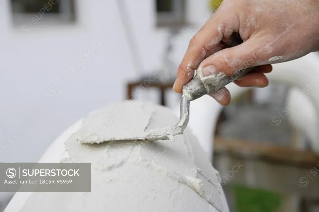 Germany, Upper Bavaria, Munich, Schaeftlarn, Sculptor applying plaster with trowel