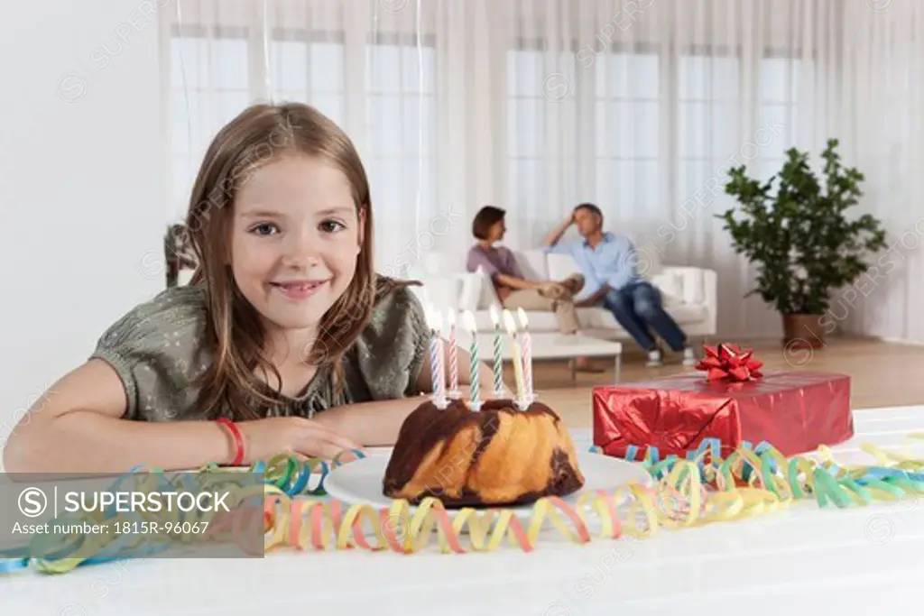 Germany, Munich, Girl with birthday cake, parents in background