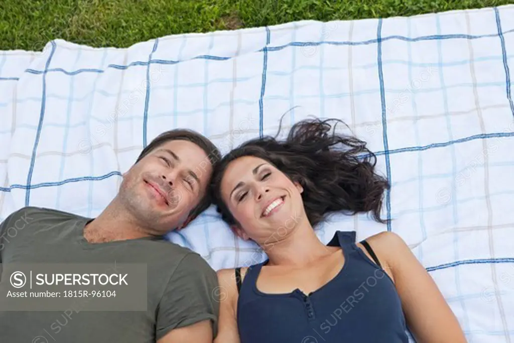 Germany, Bavaria, Couple lying on blanket in park, smiling