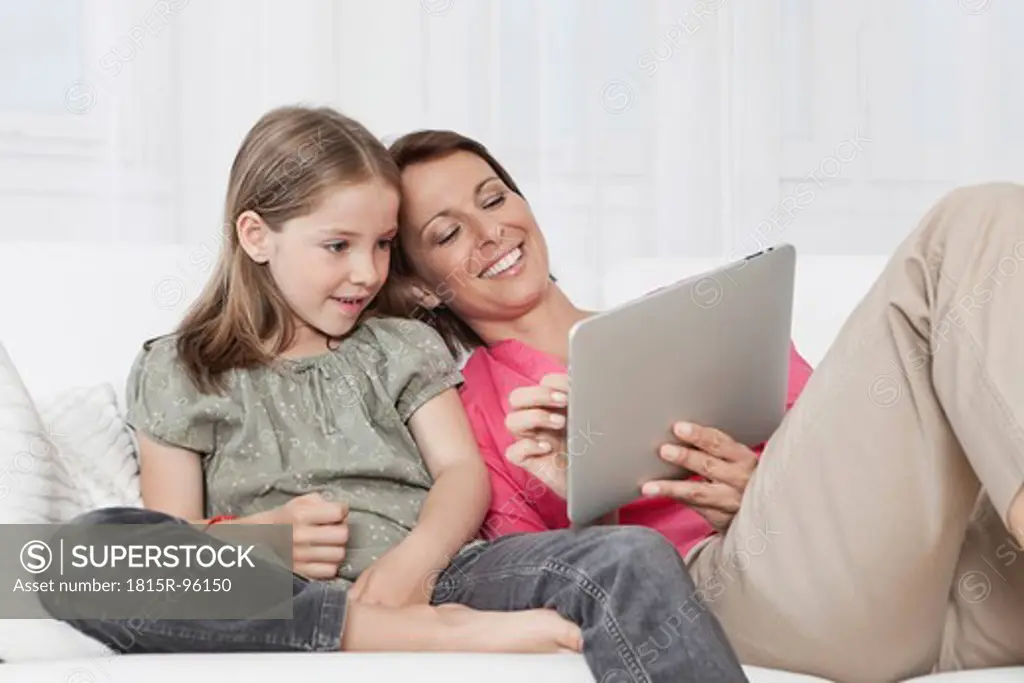 Germany, Munich, Mother and daughter using digital tablet, smiling