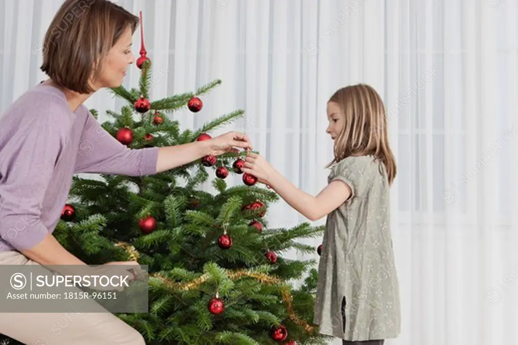 Germany, Munich, Mother and daughter decorating christmas tree