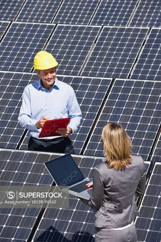 Germany, Munich, Engineers with laptop and discussing in solar plant
