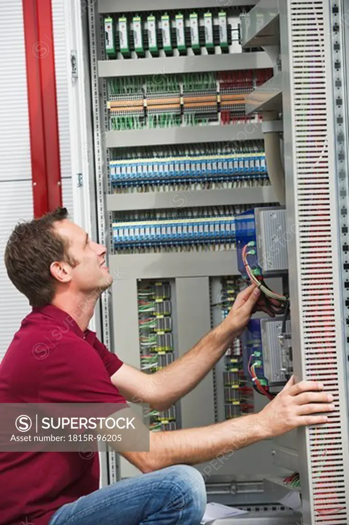 Germany, Munich, Technician fixing cable wires of circuit board