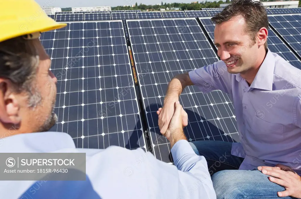 Germany, Munich, Man shaking hands with engineer in solar plant, smiling